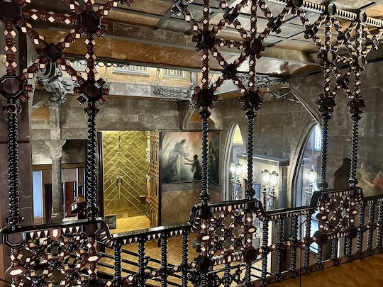 The central hall of Gaudí's Palau Guëll is richly ornated with paintings and exclusive woodwork. It looks like a church.