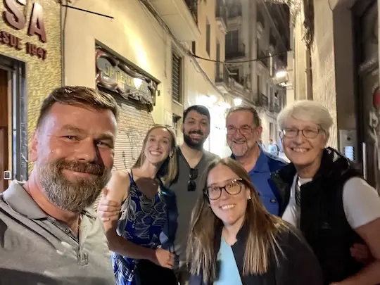 Group of smiling guests with guide Christian on the left in a narrow side street in the old town of Barcelona
