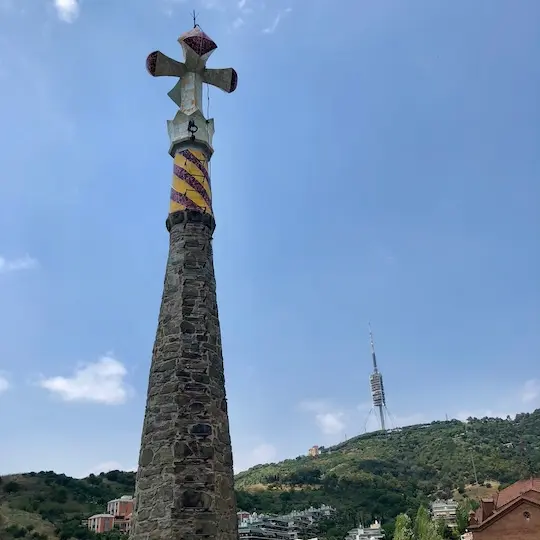The roof top spiral of the building with a Christian cross on top.
