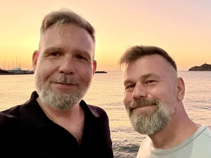Tour guides Michael and Christian in front of the sea during sun set.