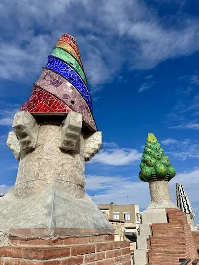 The roof top of Gaudí's Palau Guëll features colorful chimneys covered in artistic trencadís mosaics.